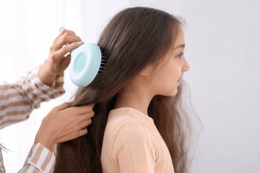 Genç anne banyoda küçük kızının saçını tarıyor.