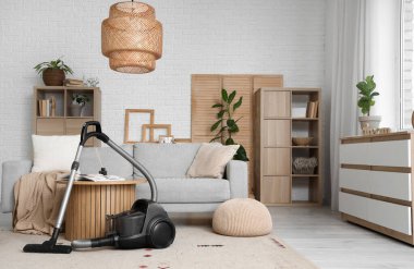 Oturma odasında elektrikli süpürge, masa ve kanepe var.