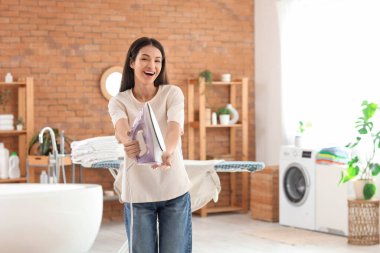 Güzel, genç ve mutlu bir kadın banyoda demirle.