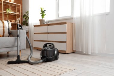 Elektrik süpürgesi, kanepe ve çekmeceleri olan bir oturma odası.