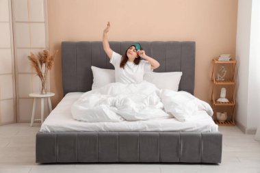 Güzel genç bir kadın sabahları yatakta geriniyor.