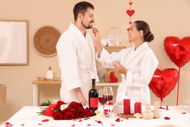 Sevgililer Günü 'nde kaplıca salonunda kocasının yüzüne masaj yapan genç bir kadın.