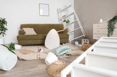 Depremden sonra kanepe ve düşen şeylerle dolu dağınık bir oturma odası.