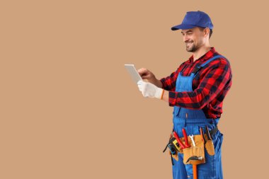 Bej arka planda tablet bilgisayar kullanan erkek teknisyen