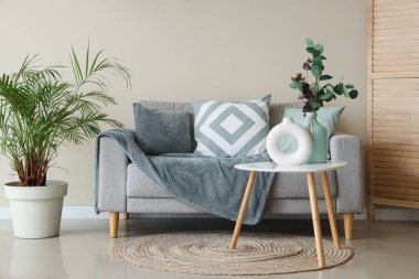 Oturma odasının içinde vazolar olan rahat bir kanepe ve kahve masası.