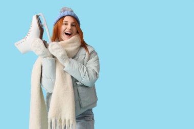 Mavi arka planda buz patenleriyle şok olmuş güzel genç bir kadın.