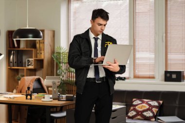 Erkek FBI ajanı ofiste dizüstü bilgisayar kullanıyor.