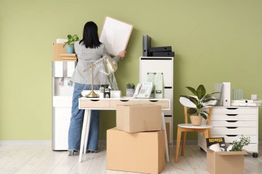 Karton kutularla dolu genç bir iş kadını taşınma gününde, arka planda