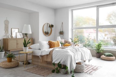 Konforlu yatağı ve çiçekleri olan hafif yatak odasının içi.