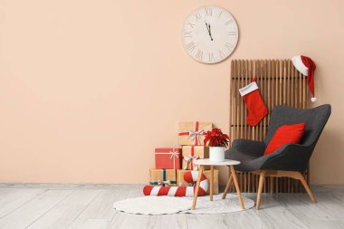 Oturma odasının içinde koltuk, katlanan ekran ve masanın üzerinde Noel çiçeği süsleri var.