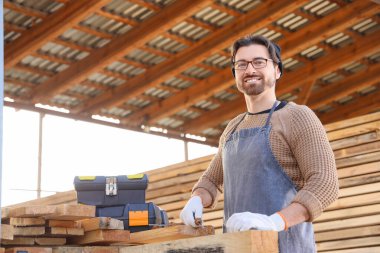 Erkek marangoz kereste fabrikasında keskiyle çalışıyor.
