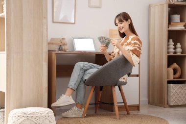 Dolar banknotları olan genç bir kadın masasının yanında oturuyor.