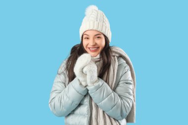 Young woman in winter clothes on blue background