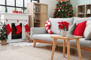 Masasında kanepe, şömine ve Noel çiçeği olan oturma odası.