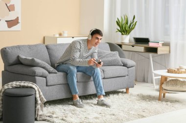 Evde video oyunu oynayan kulaklıklı yakışıklı genç adam.