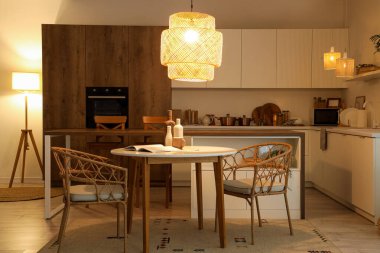 Yemek masası, tezgah ve gece lambaları olan mutfağın içi.