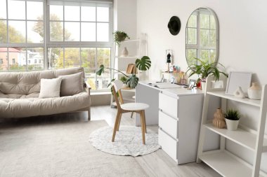 Makyaj masası, raf ünitesi ve kanepesi olan hafif soyunma odası.