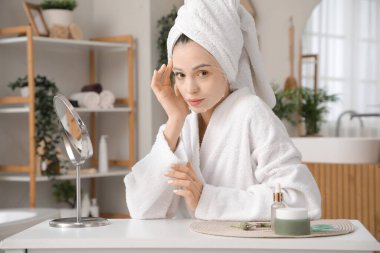 Banyodaki duştan sonra maske takan güzel bir genç kadın.