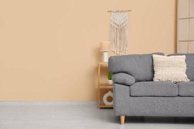 Bej duvarın yanında rahat kanepesi ve raf ünitesi olan şık bir oturma odası.