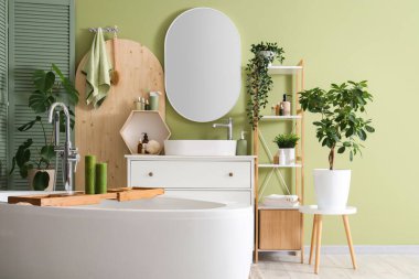 Banyonun içinde küvet, lavabo ve yeşil bitkiler var.