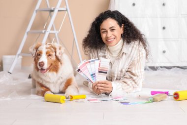 Palet örnekleriyle mutlu bir Afro-Amerikan ressam ve yeni evdeki tamirat sırasında yalan söyleyen tatlı bir Avustralya çoban köpeği.