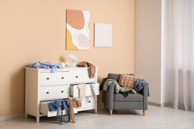 Koltuğu, klozeti ve dağınık kıyafetleri olan dağınık bir oturma odası.