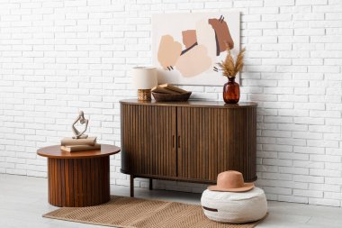 Dekorlu çekmeceler, sehpa ve beyaz tuğla duvarın yanındaki oda.