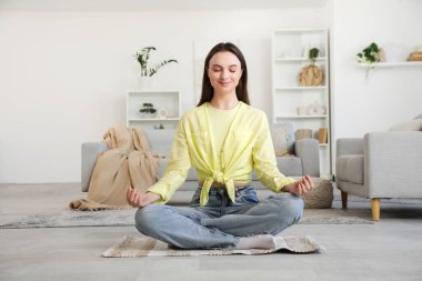 Evinde yerde meditasyon yapan güzel genç bir kadın.