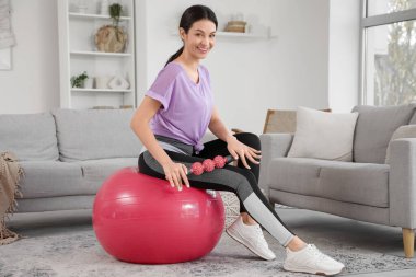 Spor yapan genç bir kadın. Vücut silindiri ile evde spor yapıyor.
