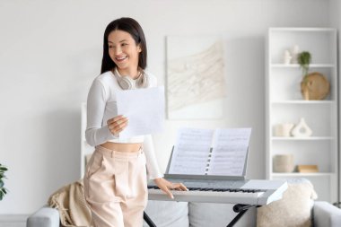 Evinde not defteri ve sentezleyicisi olan genç bir kadın.