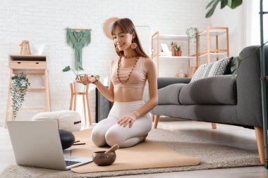 Evde meditasyon yapan genç ve güzel bir kadın.