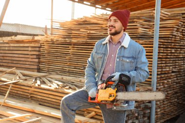 Bıçkıhanede elektrikli testereli yakışıklı marangoz.