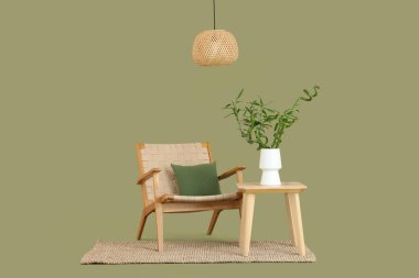 Vazoda bambu saplı masa, yeşil arka planda koltuk ve lamba.