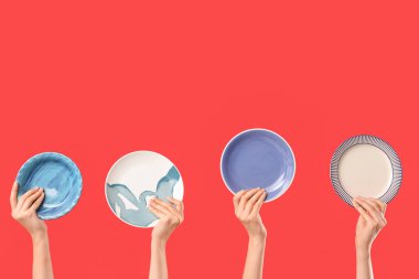 Kırmızı arka planda farklı plakalar tutan kadın eller