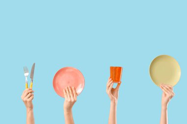 Tabakları, çatalı, bıçağı ve mavi arka planı olan kadın elleri.