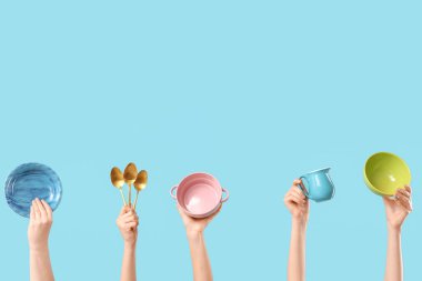 Mavi arka planda tabak, kase, sürahi ve kaşıkla kadın elleri