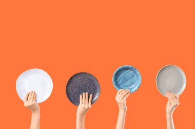 Turuncu arka planda farklı plakalı kadın elleri.