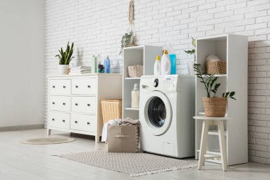 Çamaşır makinesi, çekmece ve deterjan dolu bir iç çamaşır odası.