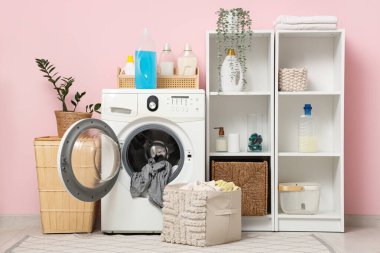 Çamaşır makinesi, sepet ve raf üniteleri olan modern çamaşır odasının içi.