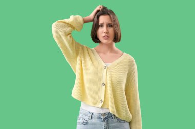 Yeşil arka planda merak eden genç bir kadın