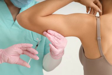 Kozmetik uzmanının ofisinde koluna iğne batırılan genç bir kadın.