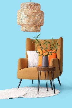 Vazoda bambu saplı masa, koltuk, halı ve lamba mavi arka planda.
