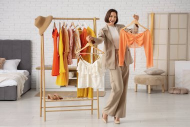 Soyunma odasında kıyafet seçen genç bir kadın.