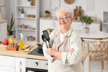 Mutfakta spatulası olan yaşlı bir kadın.