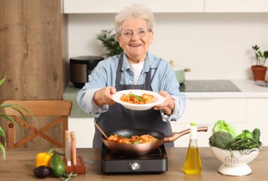 Mutfakta kızarmış makarnası olan son sınıf kadını.