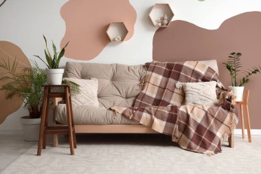 Oturma odasının içinde kareli ekoseli ve çiçekli rahat bir kanepe.