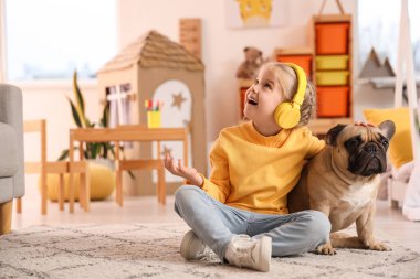 Evde oturan kulaklıklı, sevimli, mutlu, küçük bir kız.