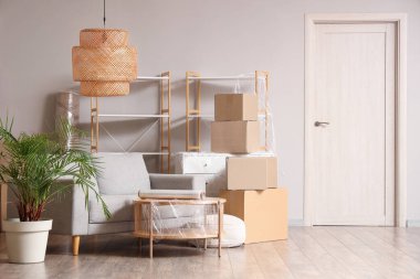 Taşındığı gün içinde gri kanepe, masa ve karton kutular olan bir oda.