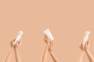 Bej arka planda kozmetik ürünleri şişeleriyle bir sürü kadın eli