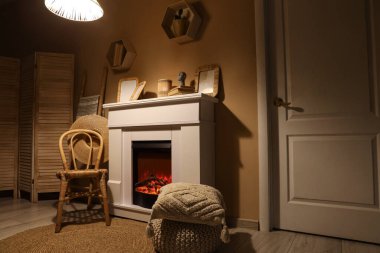 Geceleri şöminesi, koltuğu ve parlayan lambası olan karanlık oturma odasının içinde.